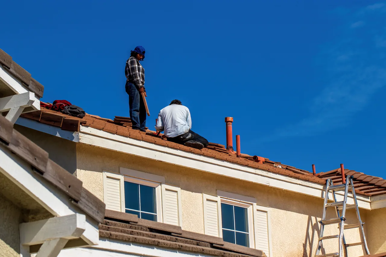 Roofers at work on a house under a deep blue sky